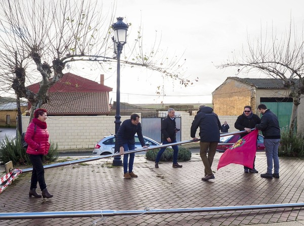 El viento arranca una bandera del suelo en Becilla durante la visita del presidente de la Diputación, Conrado Íscar, que en la imagen ayuda a moverla.  / R. VALTERO (ICAL)