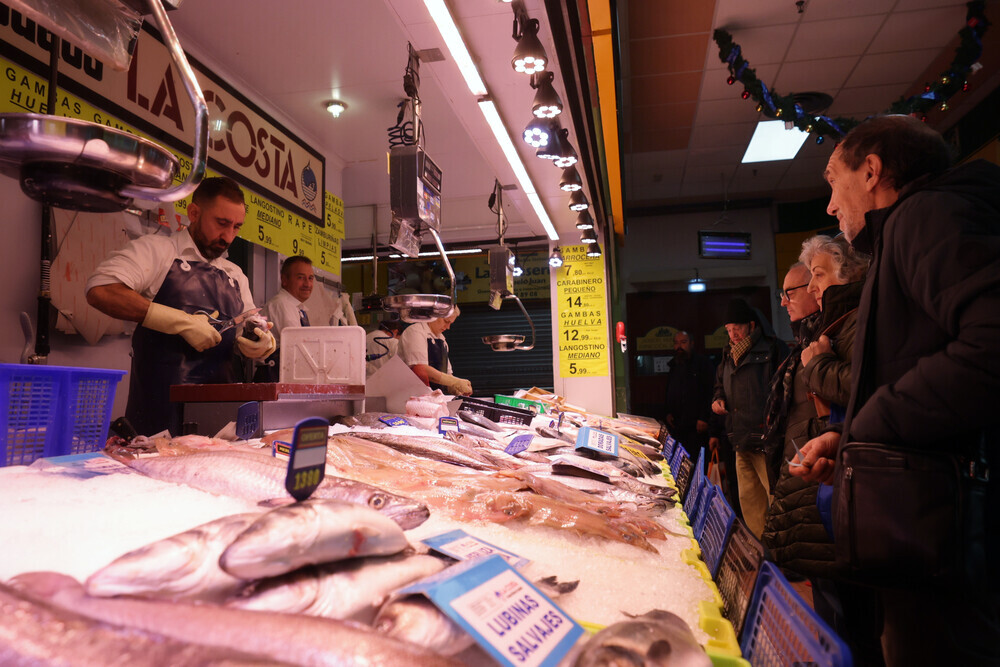 Varios clientes esperan su turno en un puesto de pescado del mercado de El Campillo. 