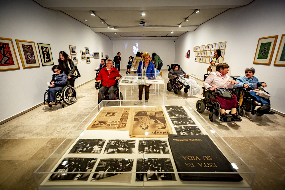 Varias personas en silla de ruedas observan las obras en una de las salas del Herreriano.